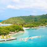 Mystery Drownings Shake New $600M Resort Tropical beach with docks and lush green hills.