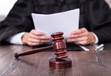A judge holding documents with a gavel in the foreground