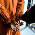 Shocking Error Jails Innocent Dad — Misses Childbirth Handcuffed person in orange jumpsuit being escorted