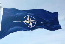 NATO on HIGH ALERT: Russian Jets Violate Airspace NATO flag waving against blue sky.