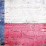 Student MOCKS Assassination — Abbott STRIKES Back Texas flag displayed on a wooden background