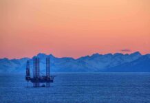 WESTERN ALLIANCE Fractures Over Trump’s Oil Stand An oil rig in the ocean with a backdrop of mountains during sunset