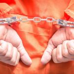 Shocking Arrest: Three Wives, One Husband! Hands in handcuffs wearing an orange jumpsuit