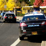 Rising Violence: Schools Under Siege? Police cars and school buses on a road