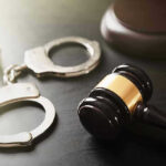 Gavel and handcuffs on a dark surface
