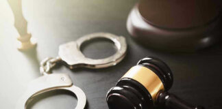 Gavel and handcuffs on a dark surface