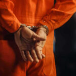 Arrest Shocker: Florida Man’s Wild 26th Bust Person in orange jumpsuit with handcuffs behind back