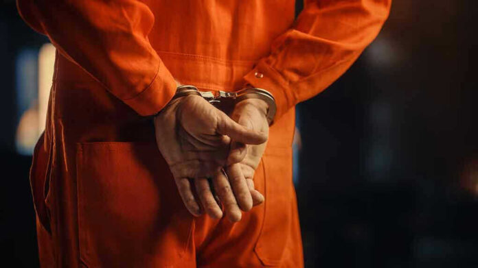 2056434935 Person in orange jumpsuit with handcuffs behind back