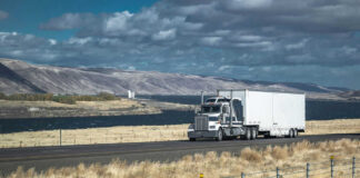 Truck driving on rural highway near river and mountains
