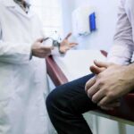 Doctor ESCAPES Punishment — Crosses State Lines A doctor in a white coat discussing with a patient sitting on an examination table