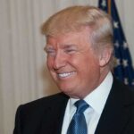 Shock 9th Circuit Ruling: Trump’s Power Upheld A smiling man in formal attire with an American flag in the background