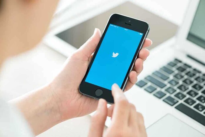 Person holding a smartphone displaying the Twitter app