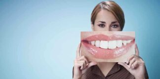 A woman holding a large image of a smiling mouth in front of her face