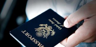 A person holding a United States passport with a dark background