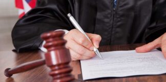 A judge signing a legal document with a gavel in the foreground