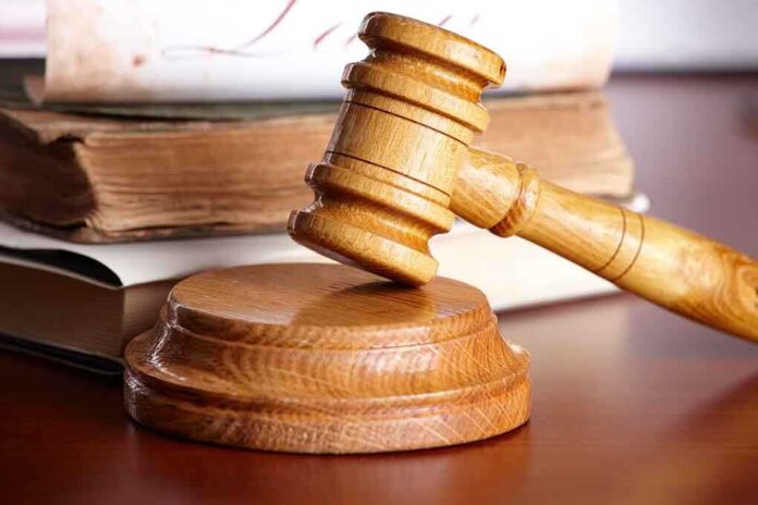shutterstock_48041785.jpg A wooden gavel resting on a circular base with law books in the background