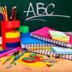 How Chinese Control Our U.S. Schools A collection of colorful school supplies including notebooks, pens, and scissors on a desk