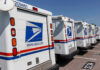 Row of USPS mail delivery trucks parked.