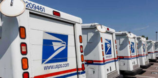 Row of USPS mail delivery trucks parked.
