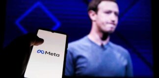 A hand holding a smartphone displaying the Meta logo with a blurred figure in the background