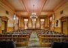 Interior view of a historic courtroom with wooden furnishings and chandeliers