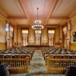 Interior view of a historic courtroom with wooden furnishings and chandeliers