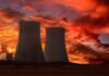 Silhouette of cooling towers against a vibrant sunset sky
