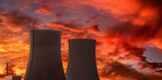 Silhouette of cooling towers against a vibrant sunset sky