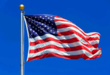 American flag waving against a clear blue sky.