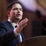 A man in a suit delivering a speech at a podium