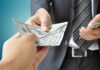Two hands exchanging cash in a business setting
