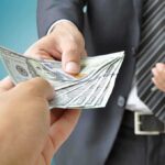 Two hands exchanging cash in a business setting