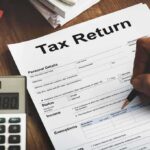 Contractor JAILED After Stealing Trump’s Tax Returns Person filling out a tax return form with a calculator nearby
