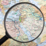 Saudi Under Siege: Iran-Linked Strikes Escalate Magnifying glass over Middle East map highlighting Israel and Egypt.