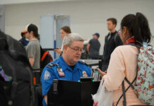 TSA agent checks passengers documents at airport security.