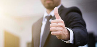 Person in suit giving thumbs up gesture.