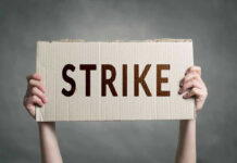 Two hands holding a cardboard sign saying STRIKE.