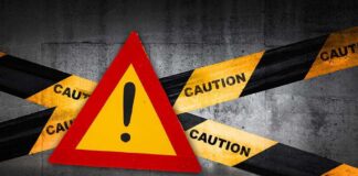 Warning sign with caution tape against a concrete background