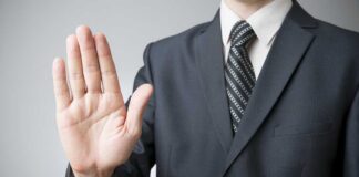 A man in a suit holding up his hand in a stop gesture