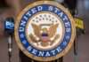 Official seal of the United States Senate with microphones in the background