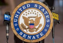 Official seal of the United States Senate with microphones in the background