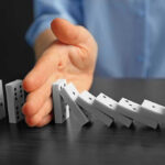 Catholic Preschools BLOCKED From Taxpayer Program They Funded Hand stopping falling row of dominoes.