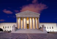 The Supreme Court building illuminated at night with a clear sky
