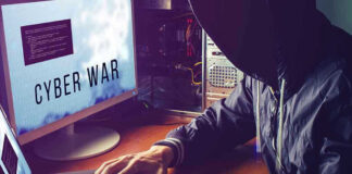Hacker typing at desk with Cyber War screen.