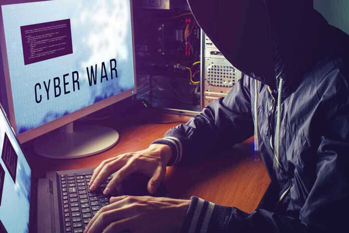 Hacker typing at desk with Cyber War screen.