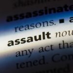 Family Trapped As Carjacker Forces In Close-up of a dictionary page showing the definition of the word 'assault'