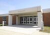 Predator Strikes in State Care – HORROR as Rape REVEALED Entrance of a modern school building with glass doors and a brick facade