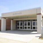 Predator Strikes in State Care – HORROR as Rape REVEALED Entrance of a modern school building with glass doors and a brick facade