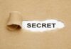 FUNDING SCANDAL — SECRET Payments to EXTREMISTS! A torn piece of brown paper revealing the word SECRET underneath