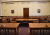 U.S. Export Controls Trigger Worldwide AI Model Shutdown Empty courtroom with wooden tables, chairs, and a door.